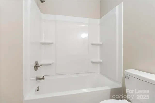 a white bath tub sitting next to a white toilet and vanity