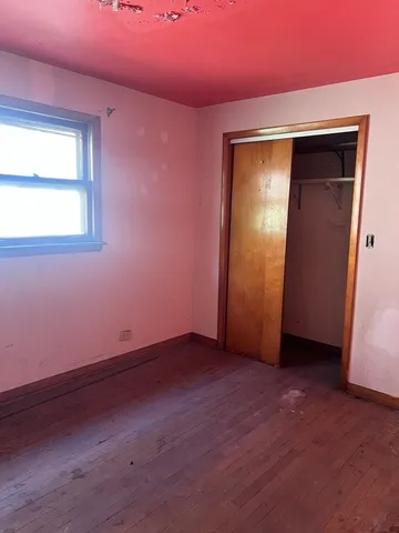 a view of an empty room with closet and a window