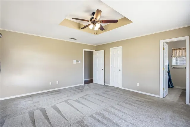 a view of an empty room with cabinet and a ceiling fan