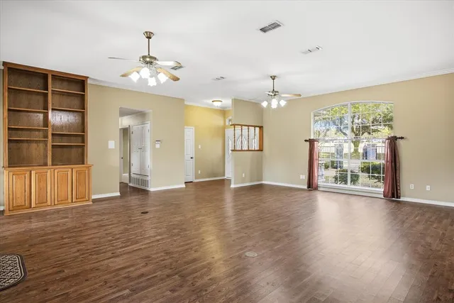 a view of an empty room with a window and wooden floor