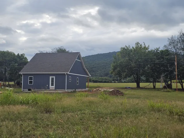 a view of an house with a big yard and large trees