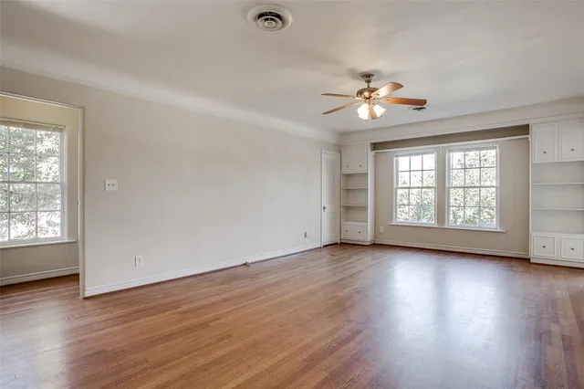 a view of an empty room with window and wooden floor