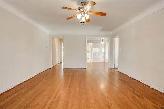 an empty room with wooden floor chandelier and windows