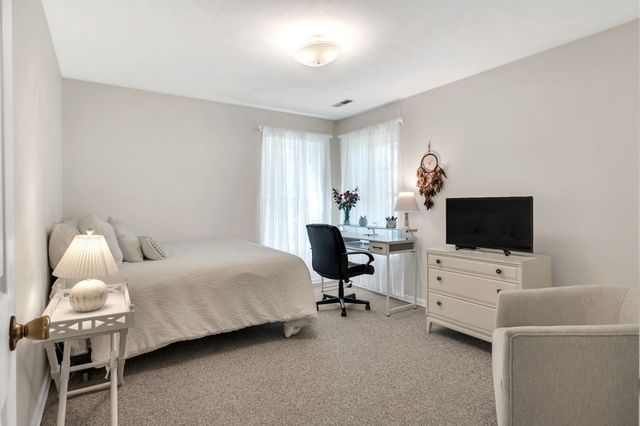 a spacious bedroom with a bed and a mirror on dresser