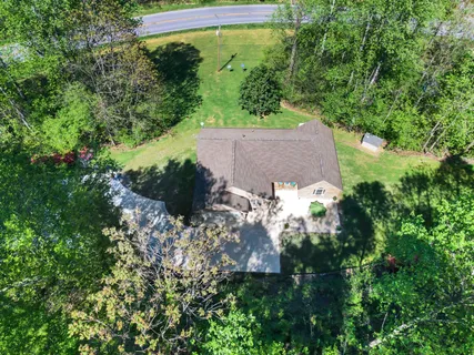 an aerial view of a house with a yard and trees all around