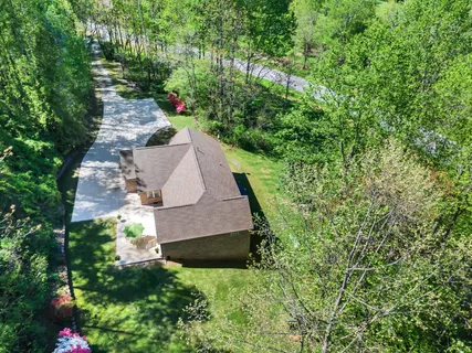 an aerial view of a house with a yard and large trees