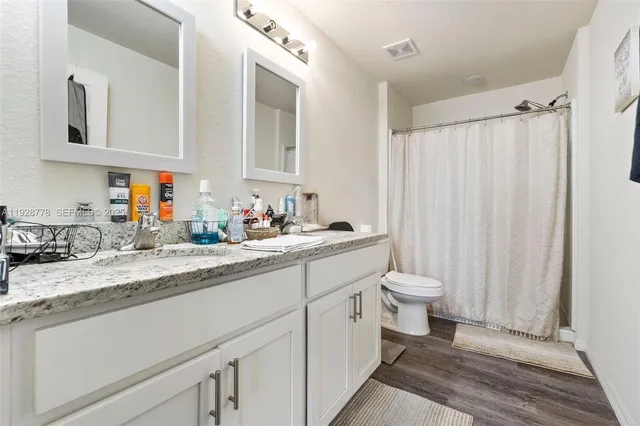 a bathroom with a granite countertop sink toilet and a mirror