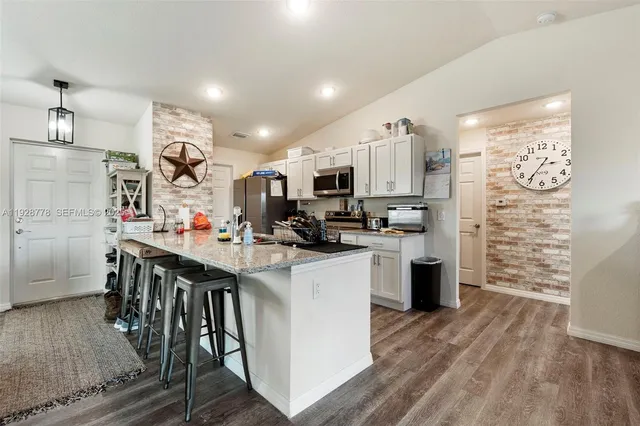 a kitchen with stainless steel appliances kitchen island granite countertop a refrigerator and a stove top oven