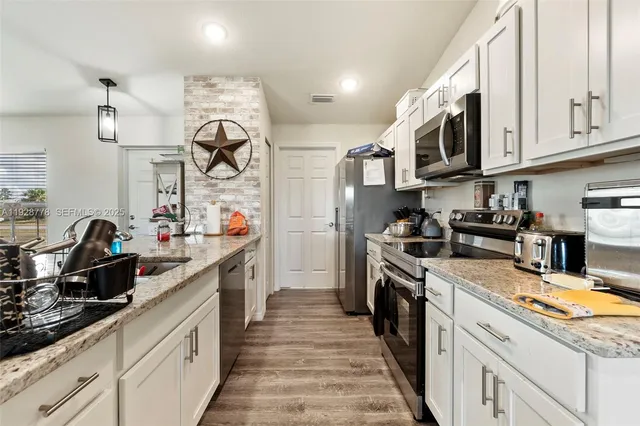 a large kitchen with stainless steel appliances granite countertop a lot of counter space and wooden cabinets