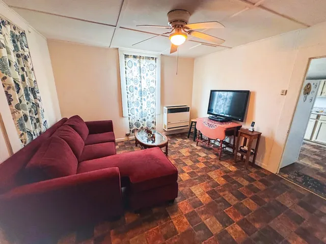 a living room with furniture a flat screen tv and a window