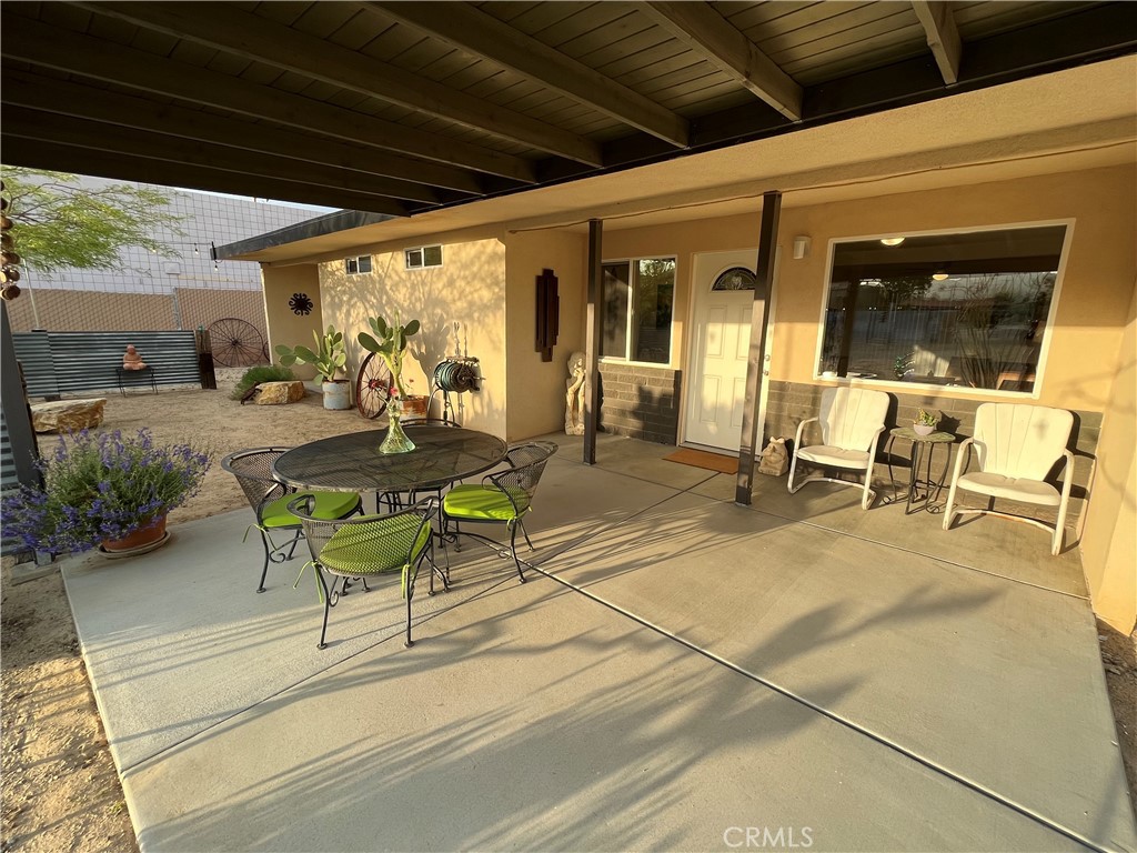 a view of a patio with table and chairs and floor to ceiling window next to a yard