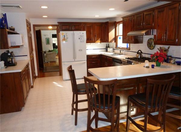 99 Maynard Farm Road Sudbury, MA 01776 - Photo 8 of 28 a kitchen with a dining table chairs refrigerator and cabinets