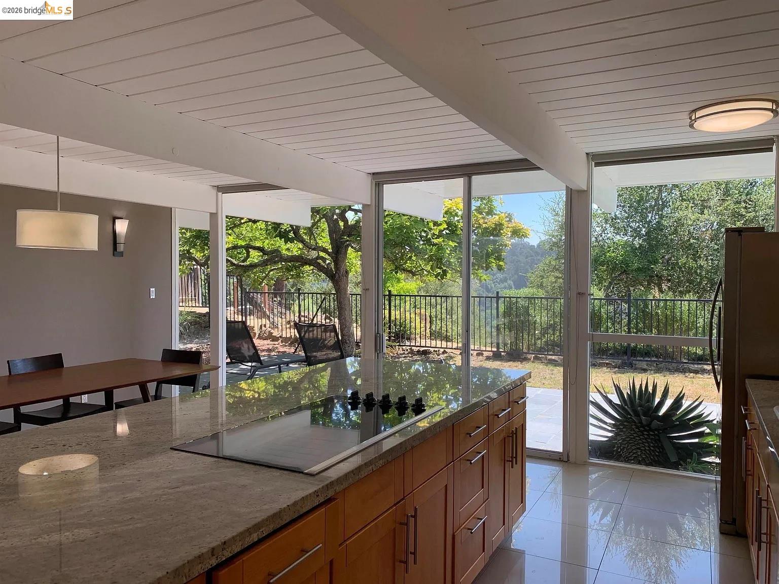 5559 Greenridge Road Castro Valley, CA 94552 - Photo 20 of 33 Kitchen with beam ceiling, floor to ceiling windows, black electric cooktop, freestanding refrigerator, and wood finish cabinetry