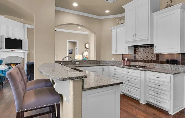 a kitchen with granite countertop white cabinets sink and stainless steel appliances