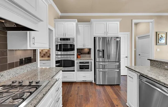 a kitchen with stainless steel appliances granite countertop a refrigerator and a stove top oven