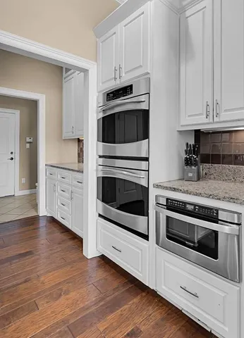 a kitchen with granite countertop white cabinets and stainless steel appliances