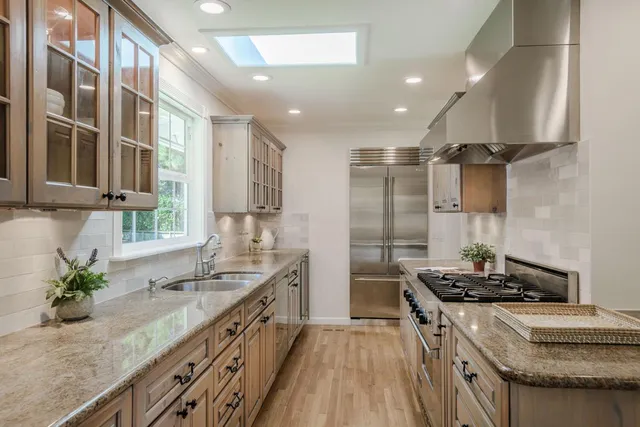 a kitchen with granite countertop kitchen island stainless steel appliances a sink stove and cabinets