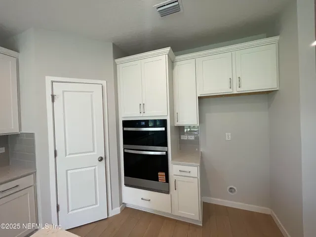 a view of kitchen with stainless steel appliances kitchen island wooden floors and living room view