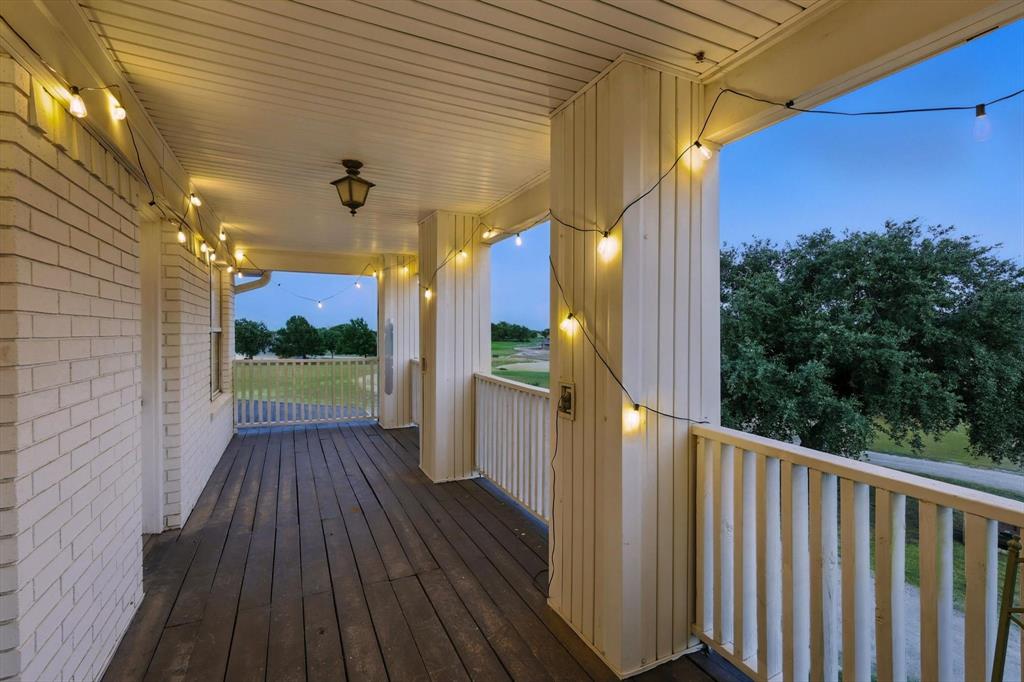 185 Quail Run Court Decatur, TX 76234 - Photo 30 of 37 Covered porch featuring white brick exterior, wood-finish flooring, white railing, and a mounted ceiling light fixture