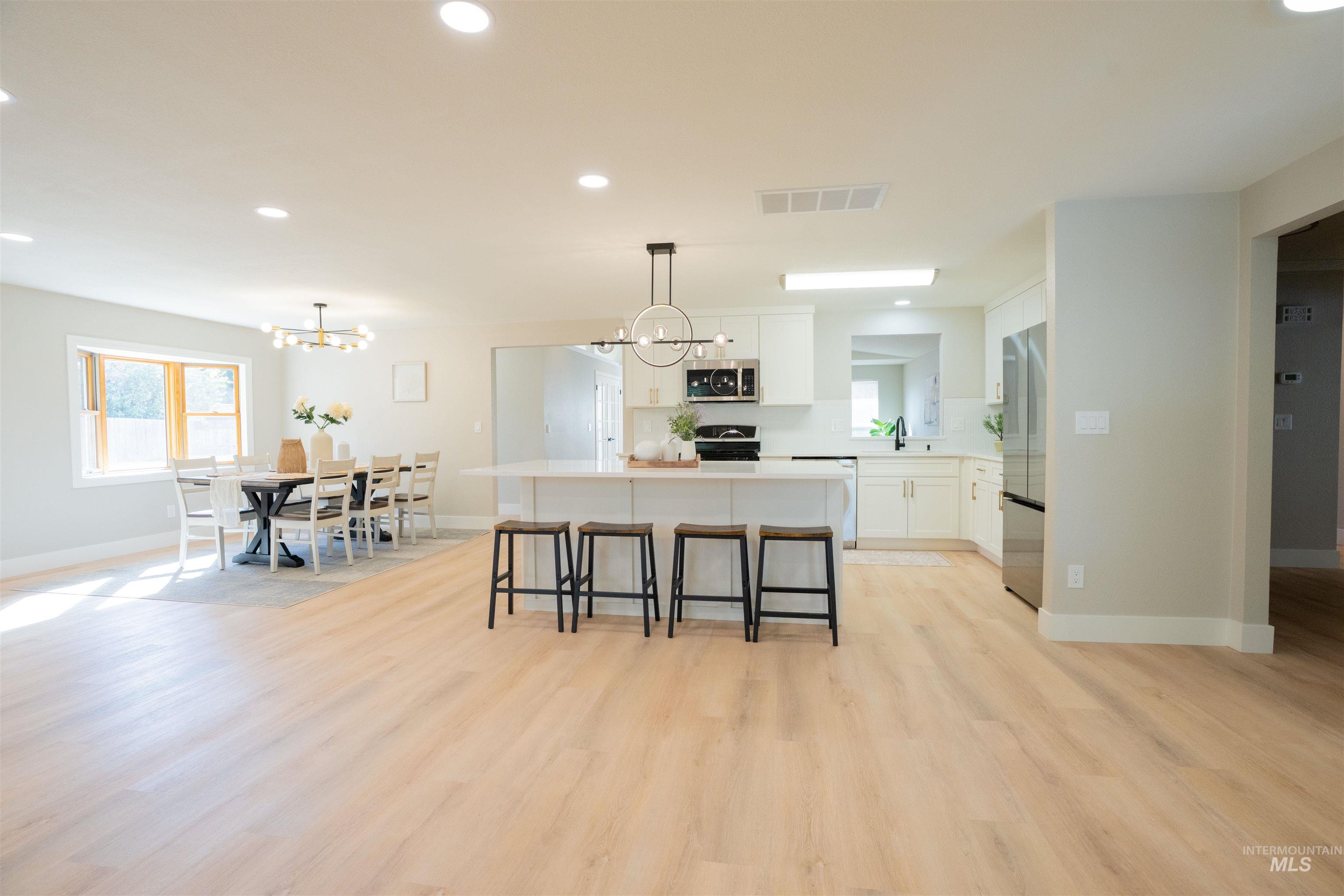 4667 Shawnee Way Boise, ID 83709 - Photo 11 of 24 Kitchen with white cabinetry, a kitchen island, recessed lighting, a breakfast bar area, and light wood-style floors