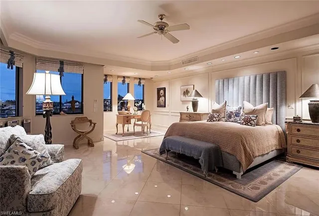 a spacious bedroom with a bed a chandelier and window