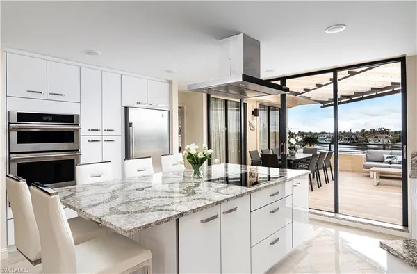 a kitchen with stainless steel appliances kitchen island granite countertop a table chairs in it and wooden floors