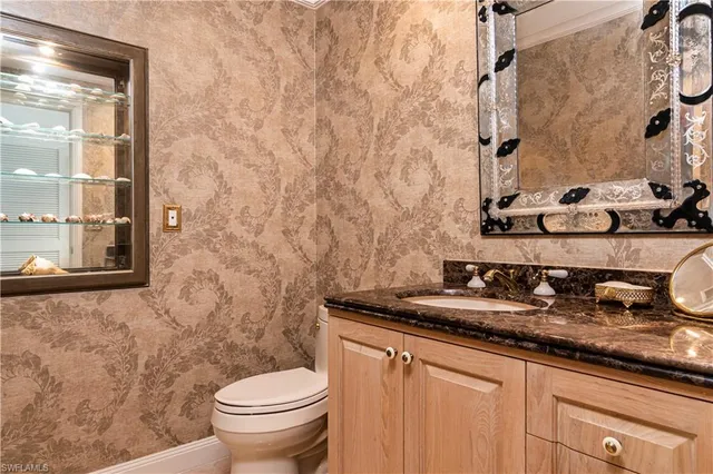 a bathroom with a granite countertop sink and a toilet