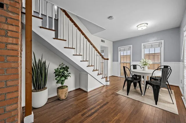 a view of a dining room with furniture a potted plant and wooden floor