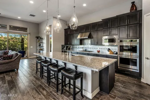 a kitchen with stainless steel appliances granite countertop a stove refrigerator and chairs
