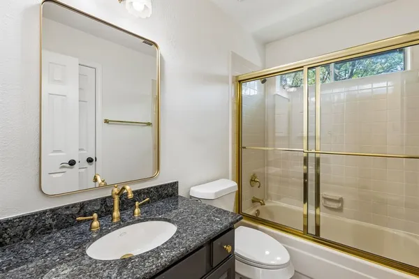a bathroom with a granite countertop sink toilet a mirror and shower