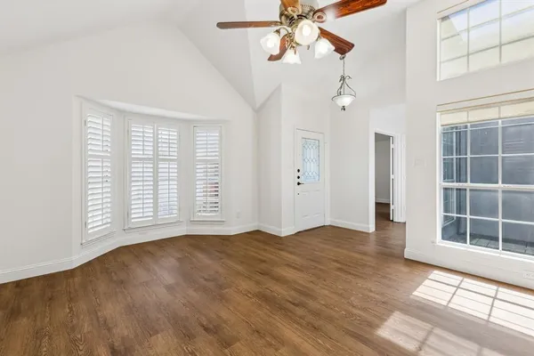 a view of an empty room with a window and wooden floor