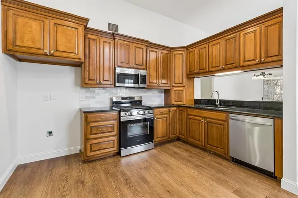 a kitchen with stainless steel appliances granite countertop a stove a sink dishwasher and a microwave oven with cabinets