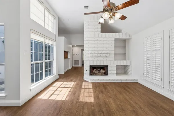 a view of a livingroom with wooden floor a fireplace and windows