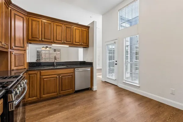 a kitchen with granite countertop wooden cabinets stainless steel appliances and a wooden floor