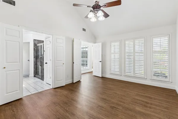 a view of empty room with wooden floor and fan