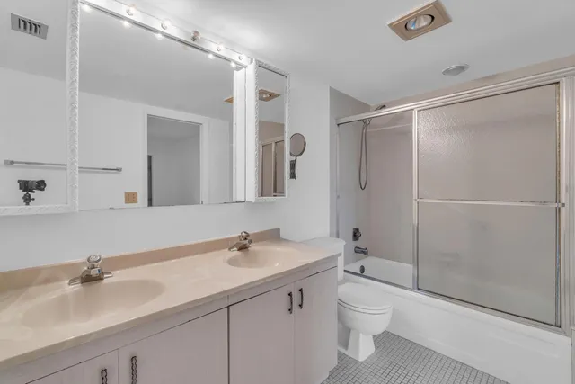 a bathroom with a double vanity sink toilet and shower