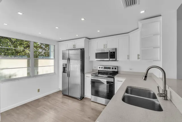 a kitchen with stainless steel appliances a refrigerator sink and microwave