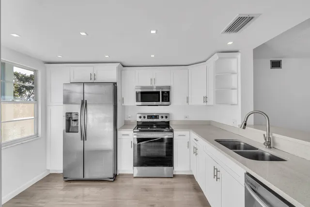 a kitchen with stainless steel appliances a refrigerator sink and microwave