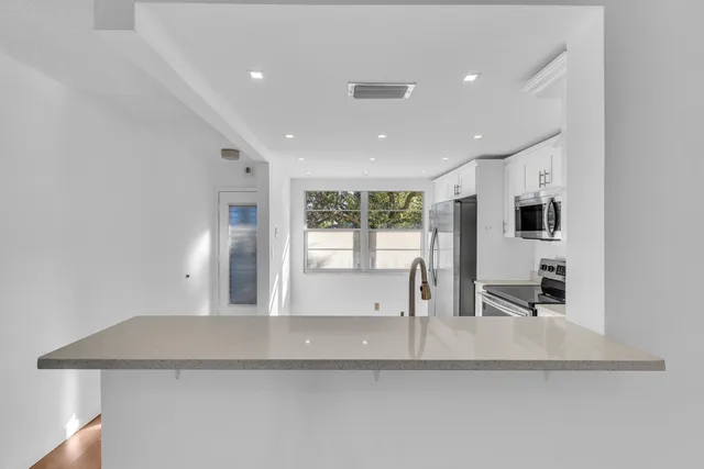 a room with stainless steel appliances a sink and a refrigerator