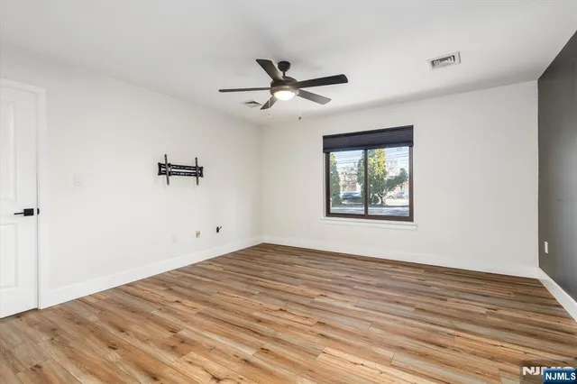 a view of an empty room with a window and a ceiling fan