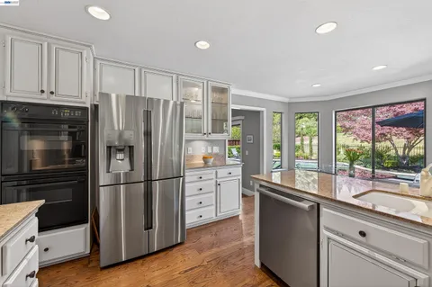 a kitchen with granite countertop a refrigerator stove and cabinets