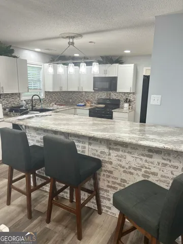 a kitchen with kitchen island granite countertop a table chairs sink and cabinets