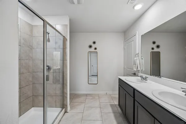 a bathroom with a double vanity sink mirror and shower