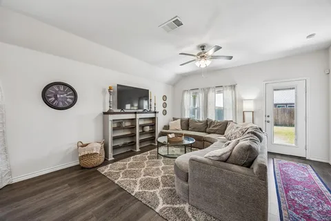a living room with furniture a flat screen tv and a ceiling fan