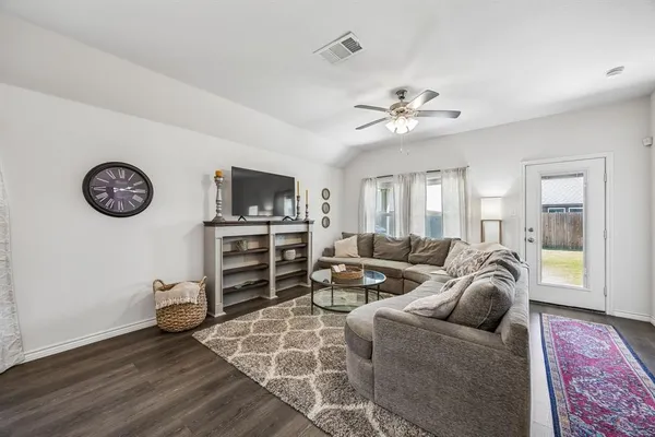 a living room with furniture a flat screen tv and a ceiling fan