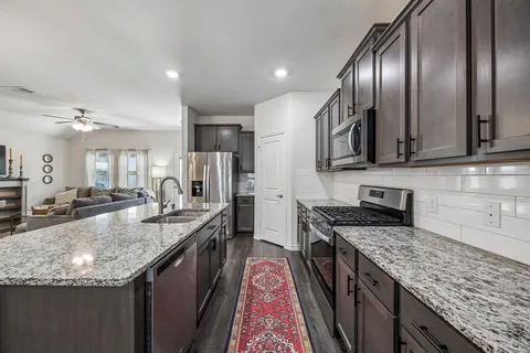 a kitchen with stainless steel appliances granite countertop a sink stove and refrigerator