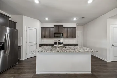 a view of kitchen with stainless steel appliances granite countertop a sink and a refrigerator