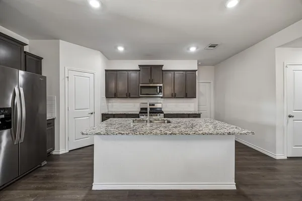 a view of kitchen with stainless steel appliances granite countertop a sink and a refrigerator