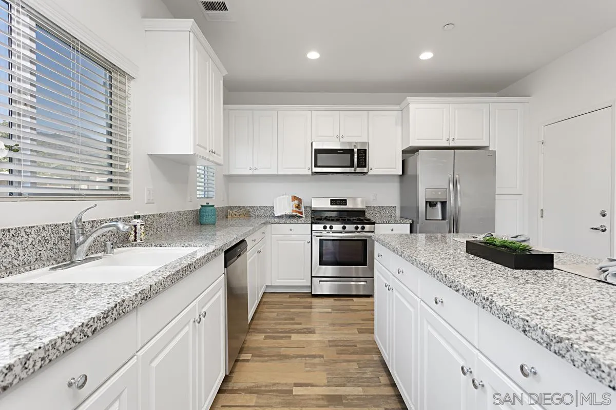 258 Windsor Grey Way Fallbrook, CA 92028 - Photo 14 of 44 a kitchen with kitchen island granite countertop a sink stainless steel appliances and white cabinets