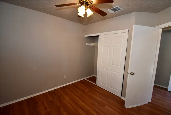 an empty room with wooden floor and fan